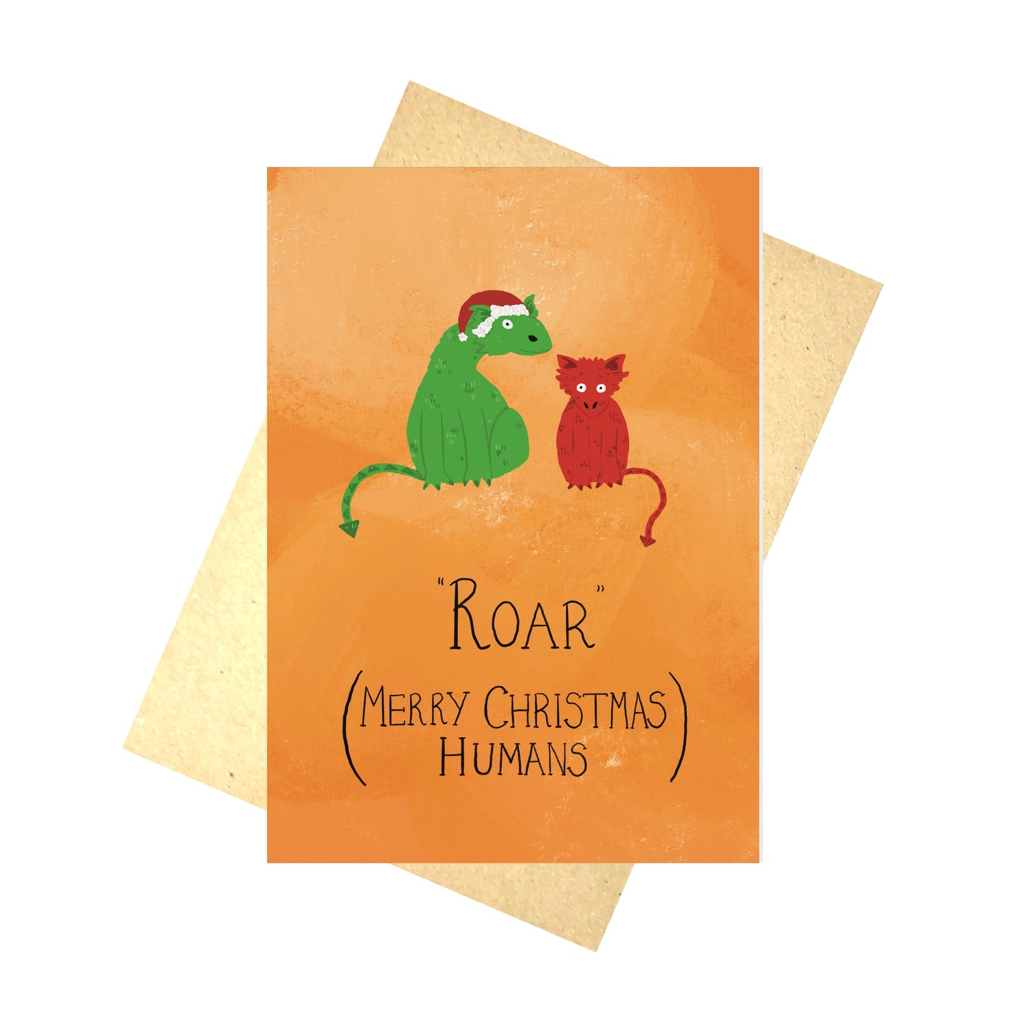 A bright orange card with a green dragon wearing a red christmas hat next to a smaller red dragon above the words 'ROAR (Merry Christmas Humans)'. The card sits in front of a brown envelope and a white background.