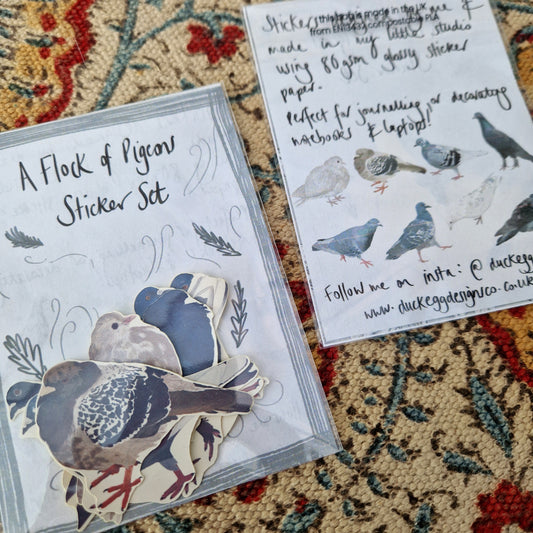 Two sticker sets next to each other - one with the top of the sticker set facing upward showing the stickers inside and one face down showing the sticker set information and the illustrations of all the stickers inside. They're both sat on a patterned fabric background.