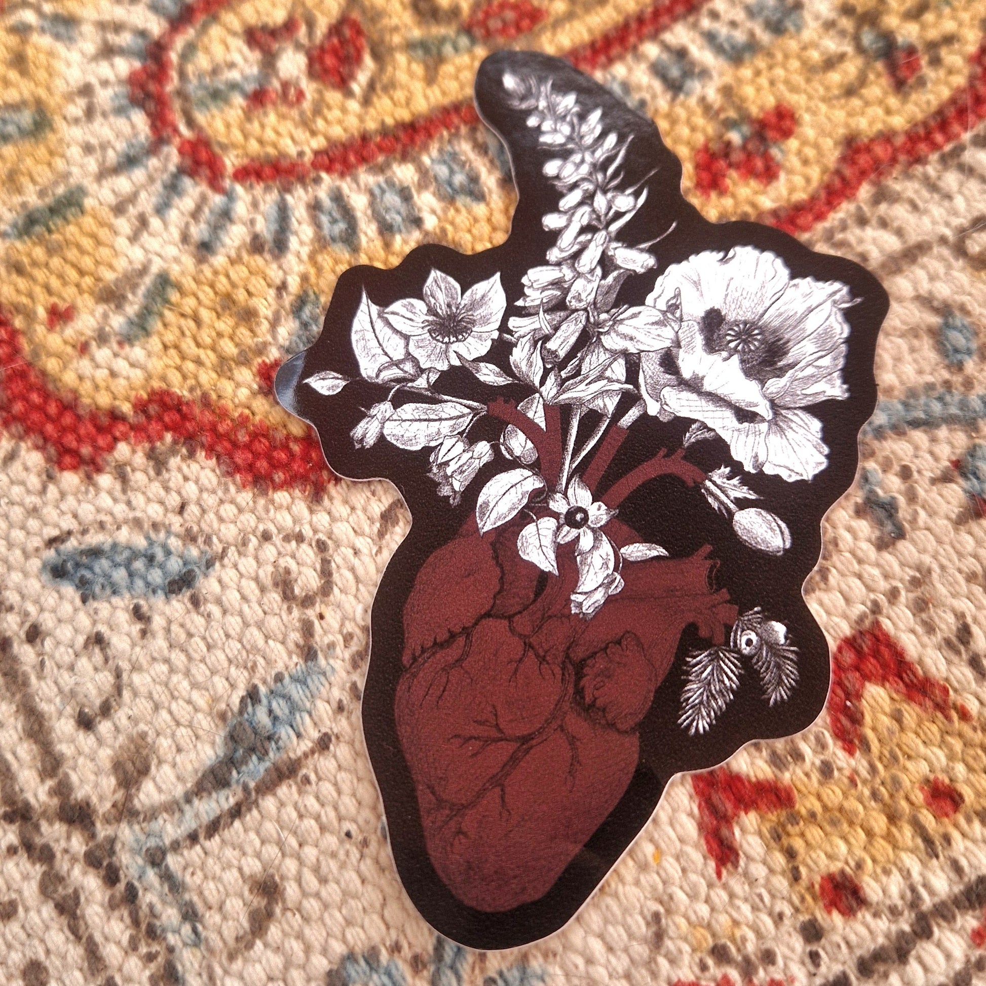 A closer look at the anatomical heart and poisonous plants sticker showing the detail in the artwork. Behing the black sticker you can see a patterned fabric background.