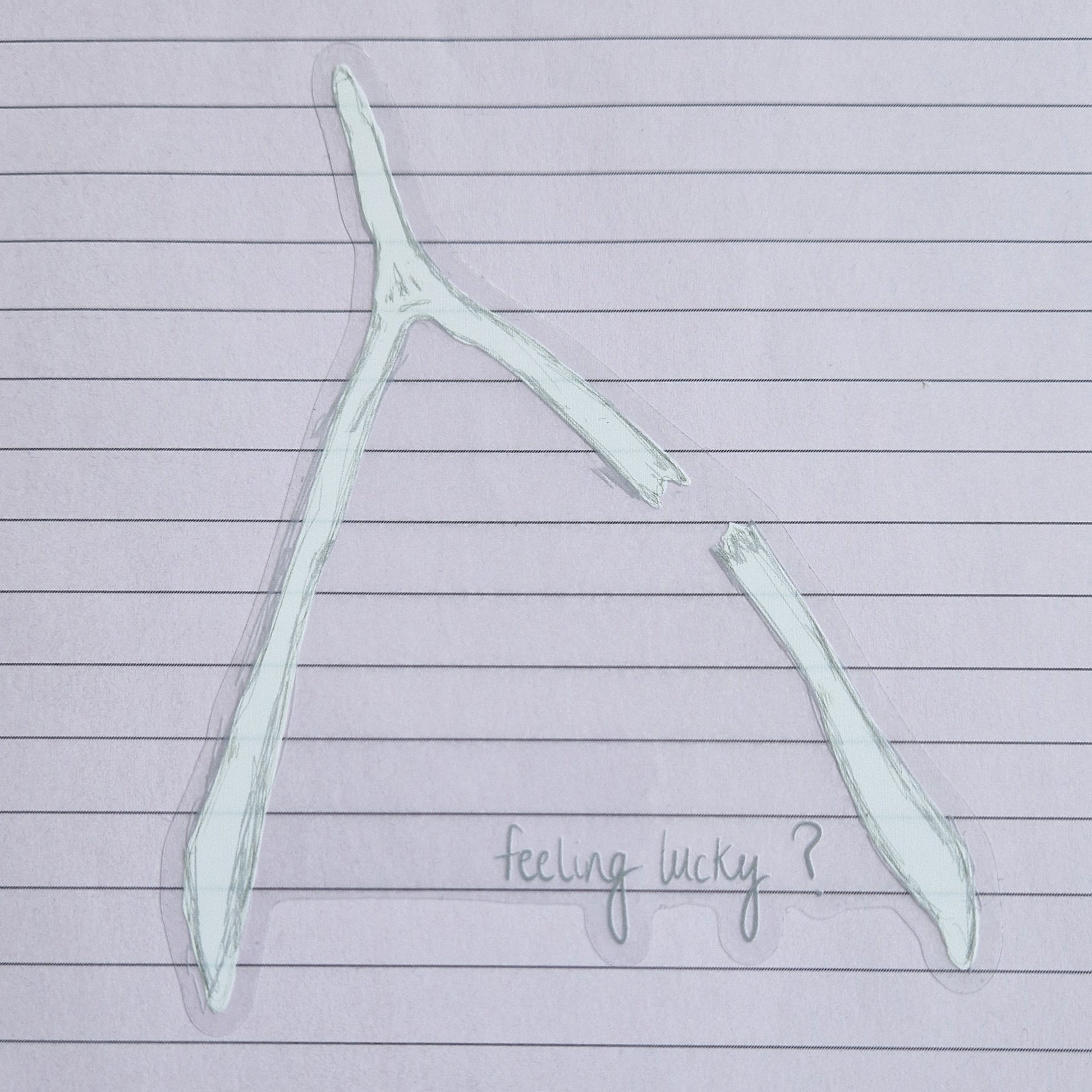 Broken wishbone sticker with the words 'feeling lucky?' written across the bottom. The sticker has a transparent background and is on a lined lilac paper.