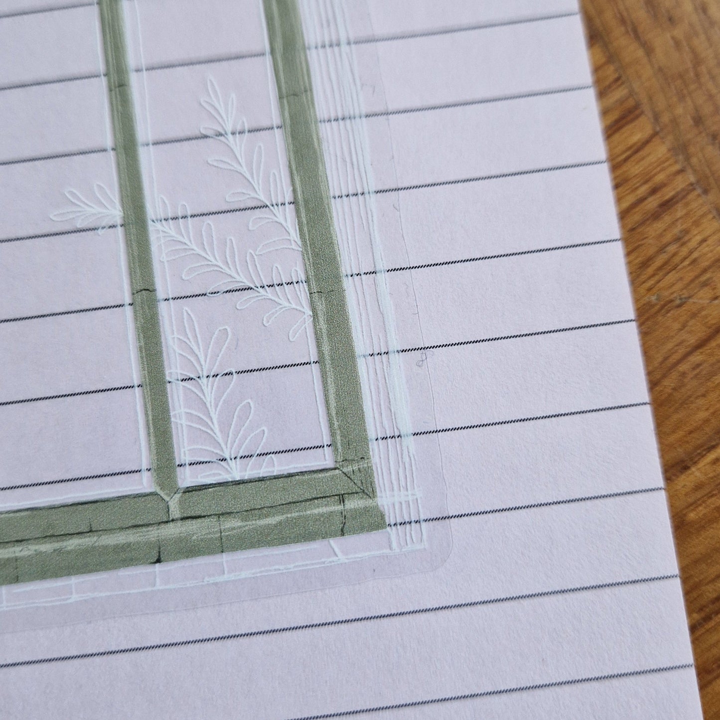 A close up of the bottom right of the transparent backgrounded cathedral window sticker showing the grey texture stone and the leafy vine illustration going across the window.