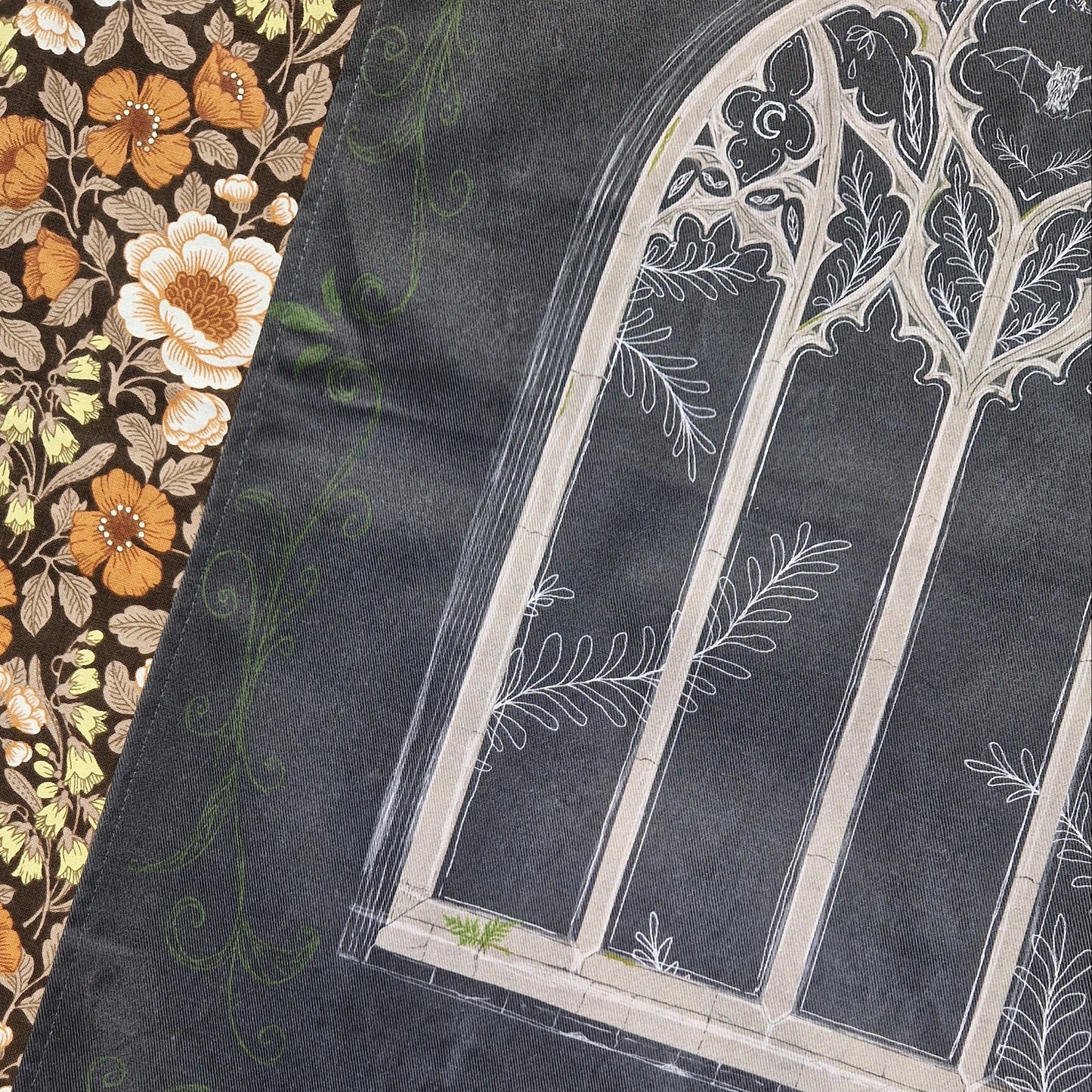 A close up of the dark grey teatowel showing the detail in the cathedral window inspired illustration.