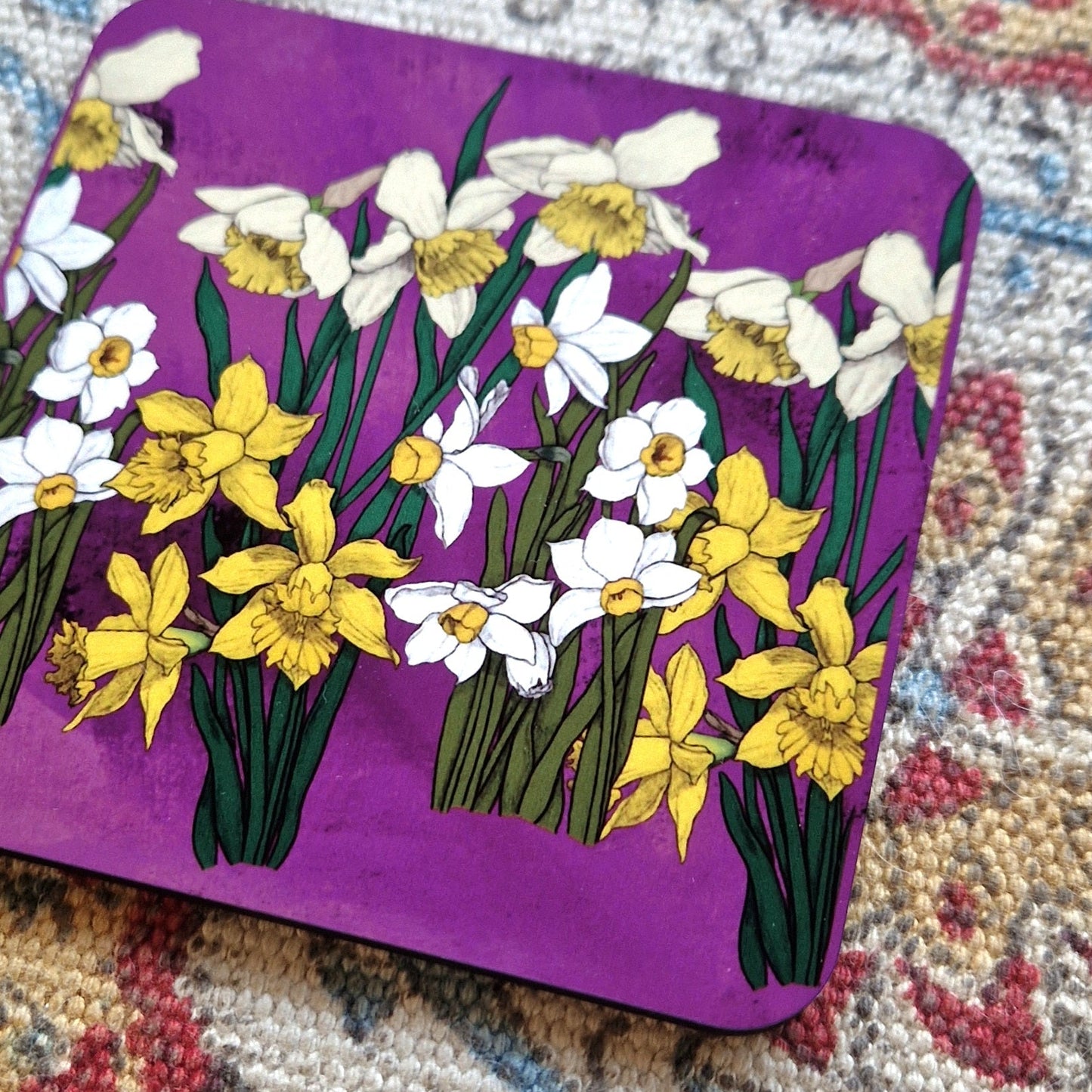 A close up view of the vibrant pink, green and yellow daffodil coaster.