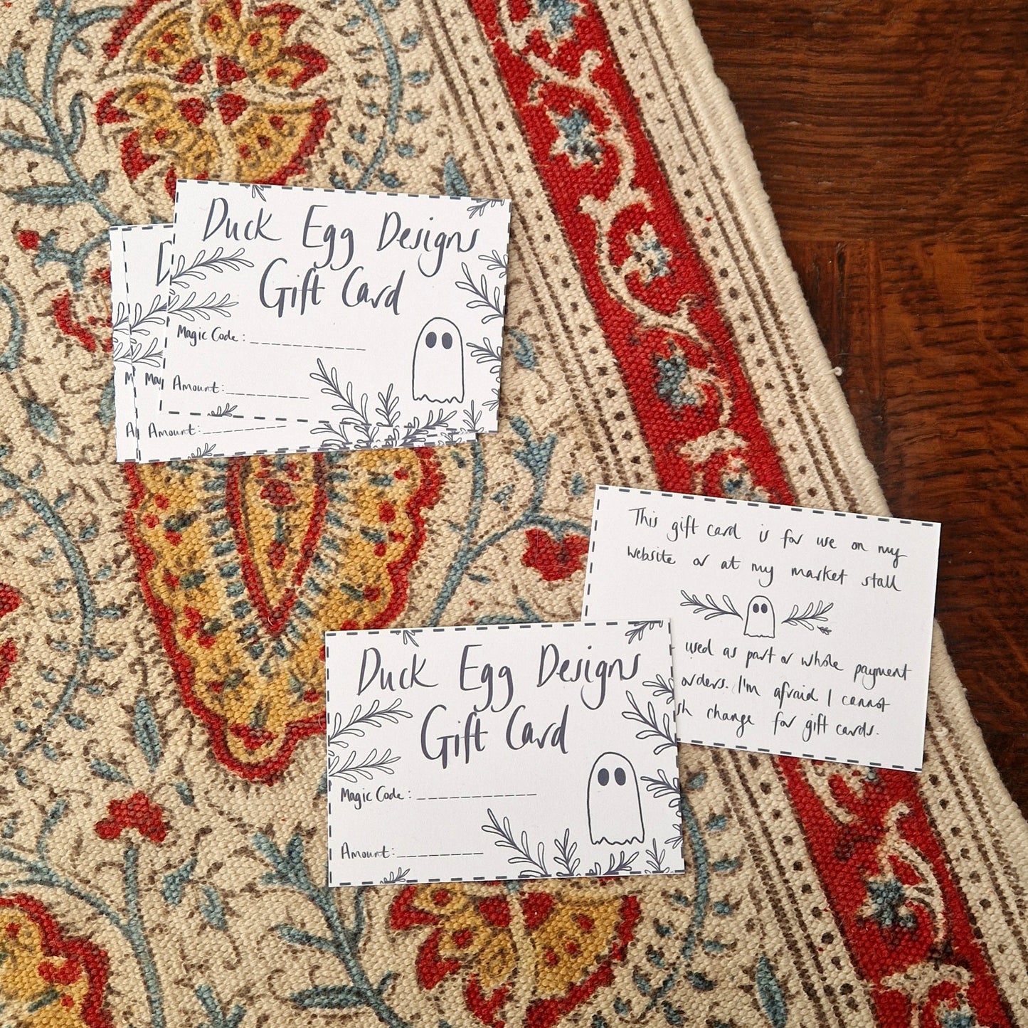 A group of Duck Egg Designs gift cards on a patterned fabric background.