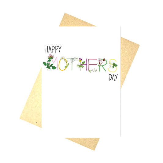 A white card with the words HAPPY MOTHERS DAY across it. HAPPY and DAY are in black, while MOTHER is in different colours, corresponding to the flowers with each letter. Behind the card is a brown envelope, behind which is a white background.