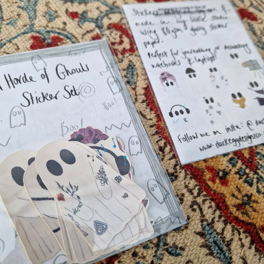 Two sticker sets sit next to each other on a patterned fabric background. One is facing up showing the ghost stickers inside and the words 'Horde of Ghouls Sticker Set' across the top in black handwriting. One is facing down showing the sticker set information and the eight different sticker designs.