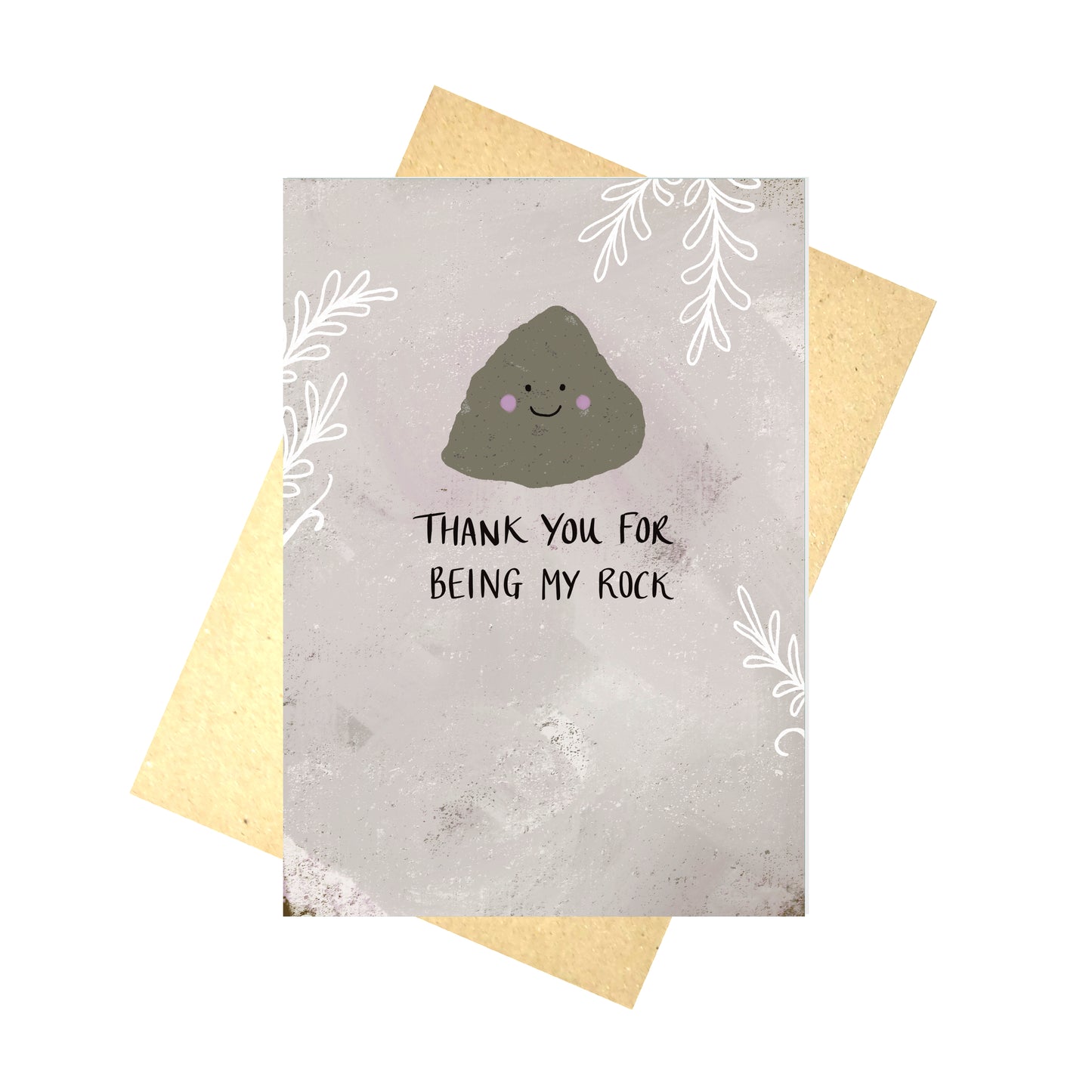 A pinkish grey card featuring a smiling rock illustration over the words 'Thank you for being my rock' in black handwriting. Around the edges of the card is a white leafy tendril design. Behind the card is a brown envelope, behind which is a white background.