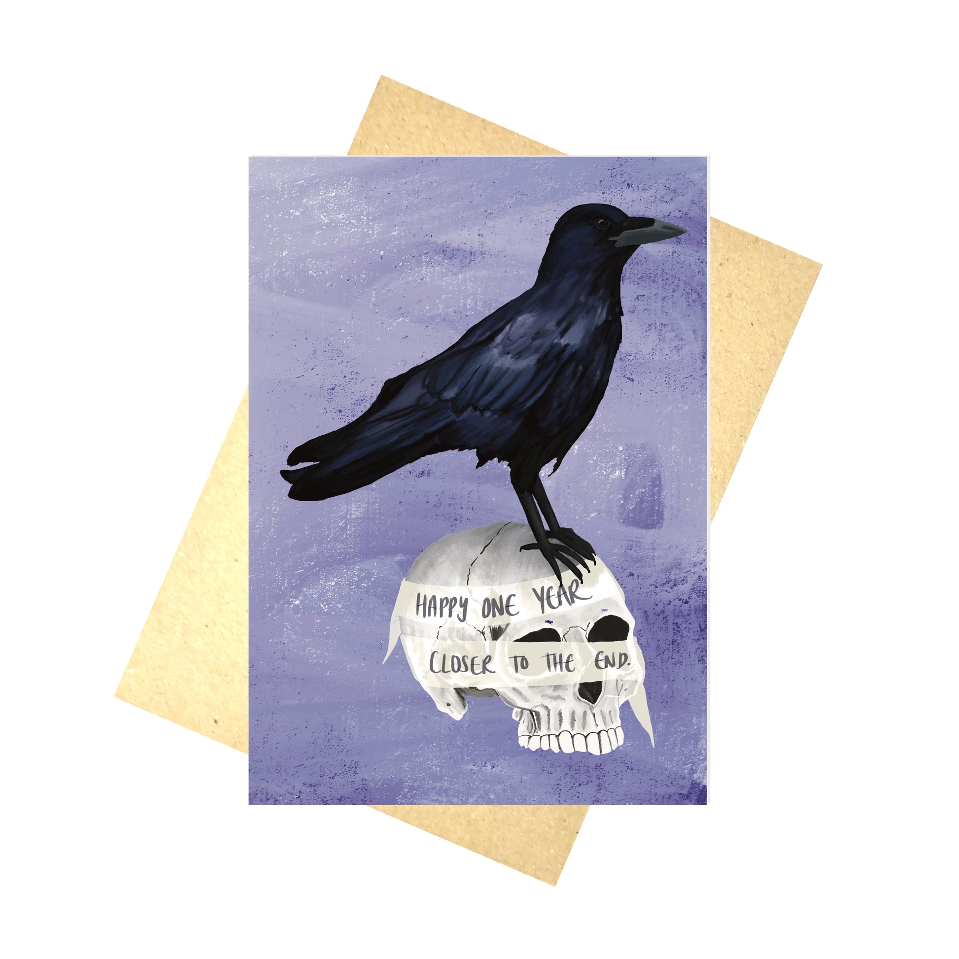 A purple greetings card with a black crow standing on a human skull with a ribbon wrapped around it. The ribbon reads 'Happy one year closer to the end'.