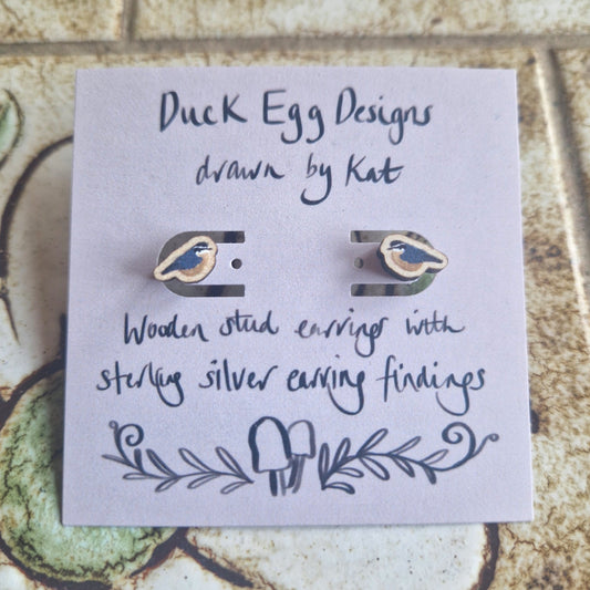 A pair of Nuthatch Bird Wooden Stud Earrings by Duck Egg Designs, crafted from FSC certified wood, with sterling silver findings. The card features the brand name and a small mushroom illustration at the bottom.