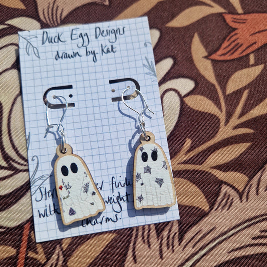 Tattooed Ghost Earrings by Duck Egg Designs feature black-eyed ghosts with colorful stars and flowers, presented on a branded card—perfect for adding whimsy to your sterling silver jewelry collection.