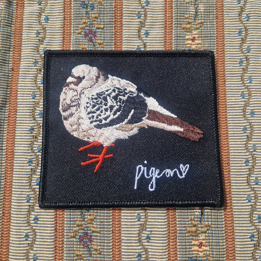 The Embroidered Bert Pigeon Patch by Duck Egg Designs features a pigeon with red legs and a white heart on black, and has an iron-on backing for easy attachment to your favorite striped or floral-patterned fabric.
