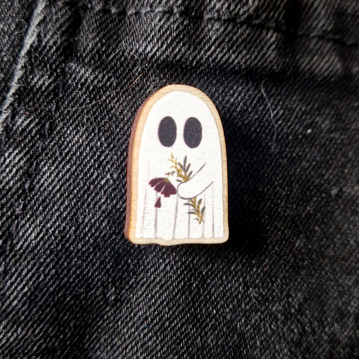 Ghost-shaped pin on a black denim background