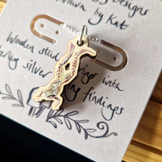 Wooden printed frog pendant on a silver chain hangs from a paper backing card.