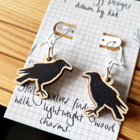 Raven shaped earrings on a card with text
